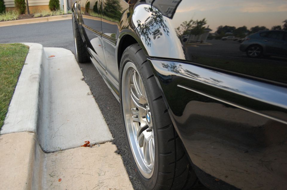Rear wheel of lowered black BMW with polished lip wheel and stretched tire
