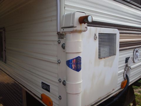 1988 Ford F-350 - Exterior view of a camper shell, showing siding, a vent pipe, and a water hookup.