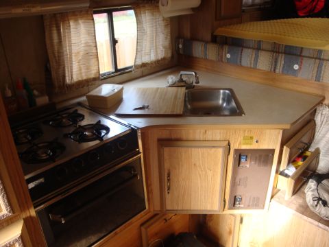1988 Ford F-350 - Interior view of an RV, a kitchen area with a stove and sink, and a sleeping area.