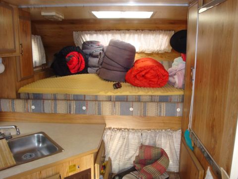 1988 Ford F-350 - The interior of a camper shows a sleeping area and a small kitchenette with a sink.