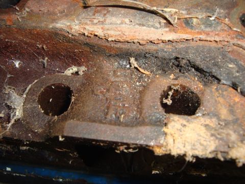 1989 Ford Bronco - This heavily corroded metal part shows casting marks but no clear identification.