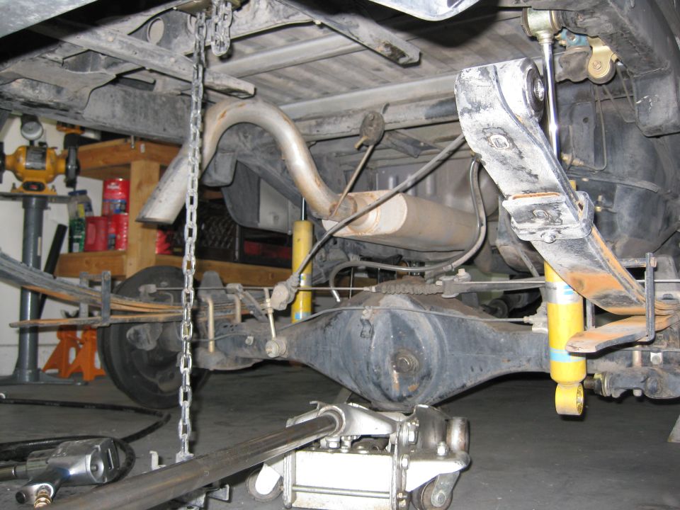Rear axle, leaf springs, shocks, and exhaust system of a vehicle being worked on