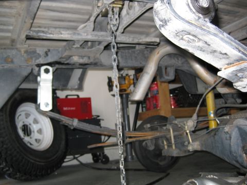 1990 Toyota Pickup/SR5 - The rear suspension and exhaust system of a pickup truck are visible, with a welding machine in the background.