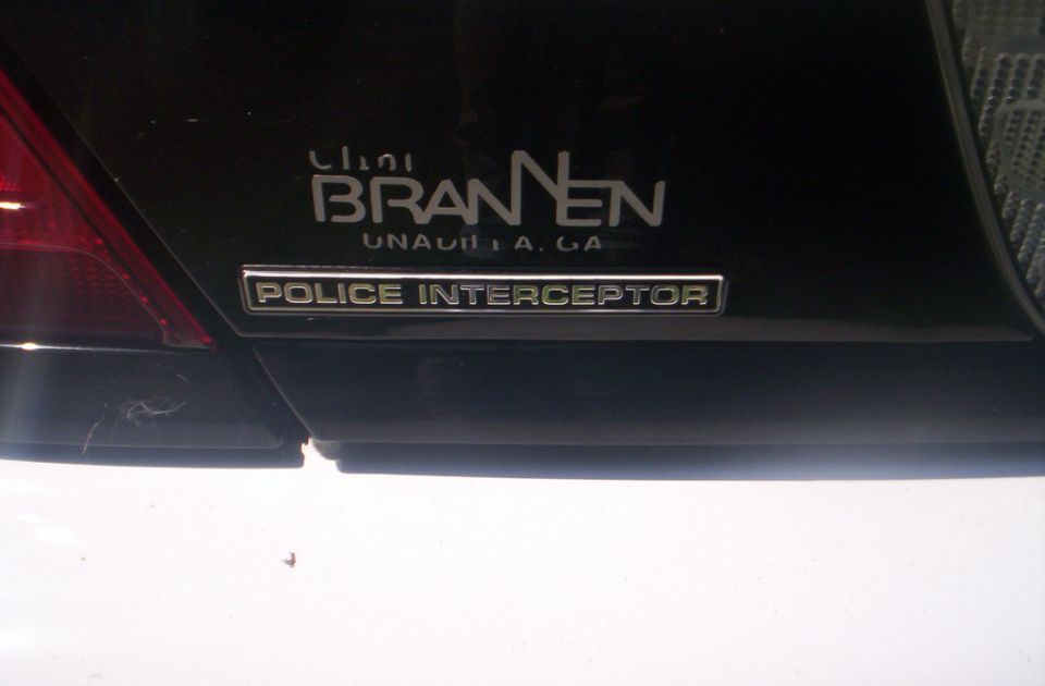 Black sedan rear with chrome POLICE INTERCEPTOR badge and Brannen dealer decal