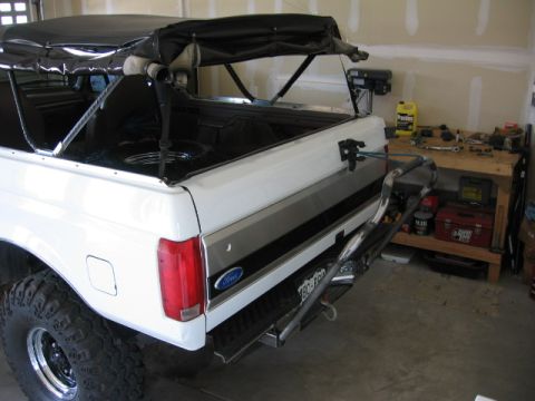 1995 Ford Bronco - Rear view of a white 1995 Ford Bronco, a soft top and a drop-down tire carrier.