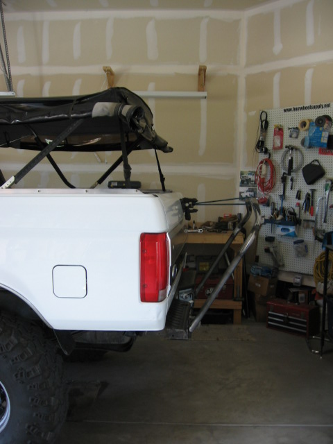 1995 Ford Bronco - Rear view of a white 1995 Ford Bronco showing a custom tire carrier and roof-mounted awning.