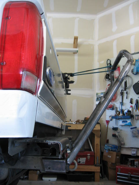 1995 Ford Bronco - The rear of a white SUV with a custom tire carrier attached to the bumper.