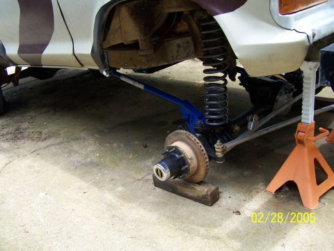 1979 Ford F-150 - The front suspension of a truck is shown with the wheel removed and supported by blocks and jack stands.