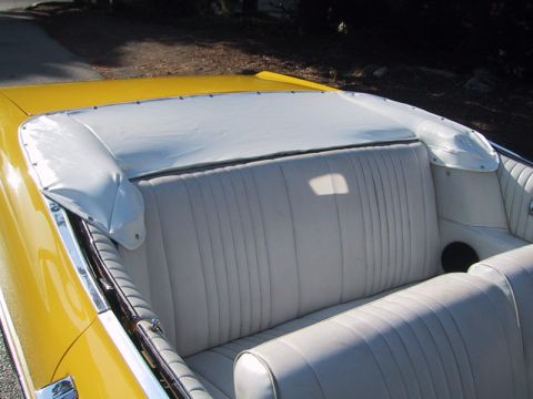 1967 Ford Galaxie - The interior of a yellow convertible shows a white vinyl bench seat and the boot cover for the soft top.