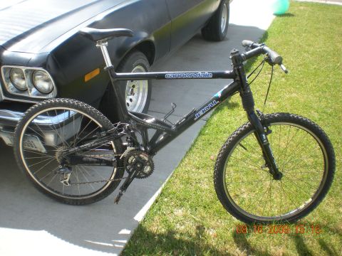 1974 Ford Ranchero - A black Cannondale Jekyll mountain bike is parked next to a black car, with a SuperMotors watermark visible.