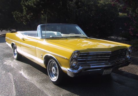 1967 Ford Galaxie - A bright yellow 1967 Ford Galaxie convertible with a white interior is parked on a wet asphalt surface.