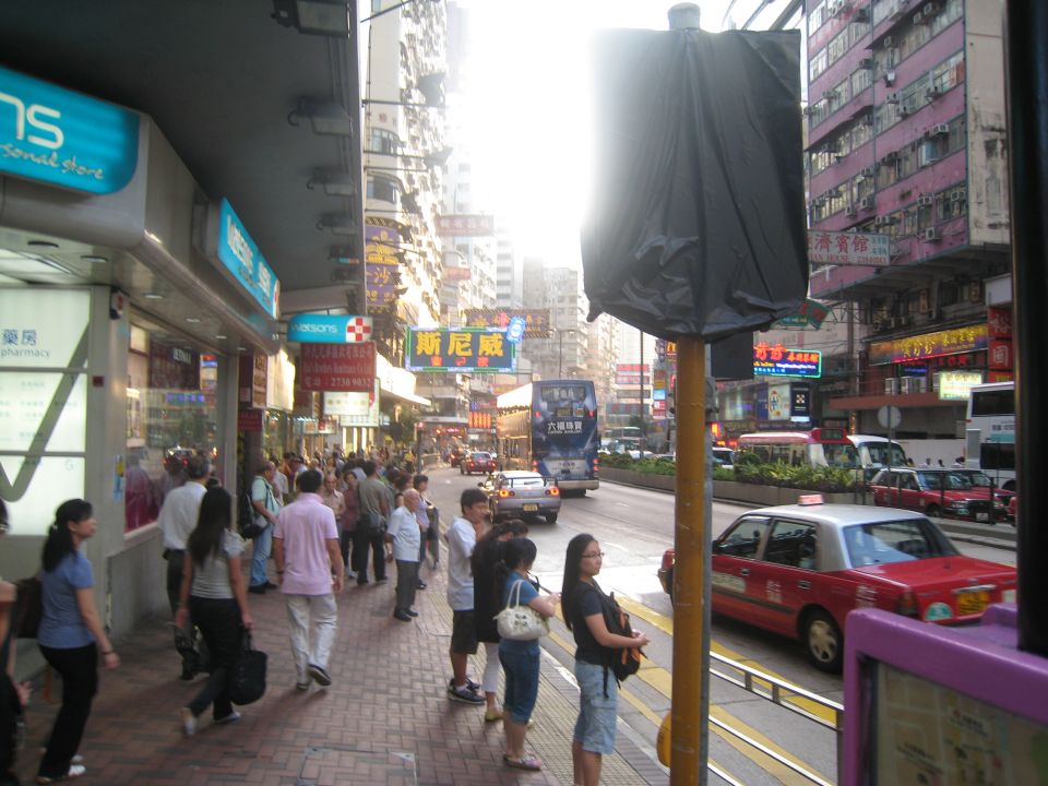 Red taxi cab driving on a busy street in a city