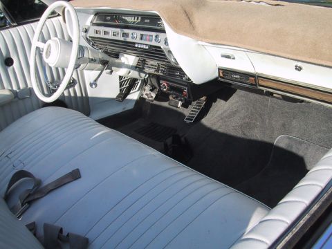 1967 Ford Galaxie - The interior of a vintage automobile showcases its white vinyl seats, dashboard, and carpeting.