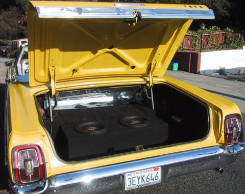 1967 Ford Galaxie - The rear of a yellow 1966 Ford Galaxie convertible is shown with the trunk open, revealing a large subwoofer box.