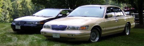 1996 Mercury Grand Marquis - A tan 1996 Mercury Grand Marquis is parked on a lawn next to a black sedan.