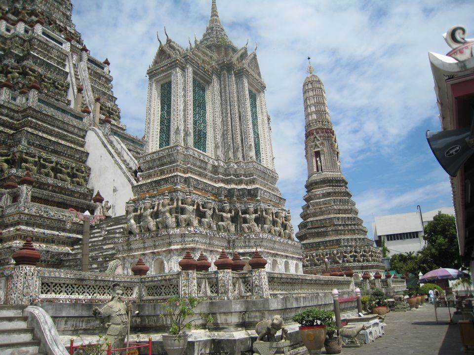 Ornate white temple structures with intricate carvings and tiered roofs under a blue sky with clouds