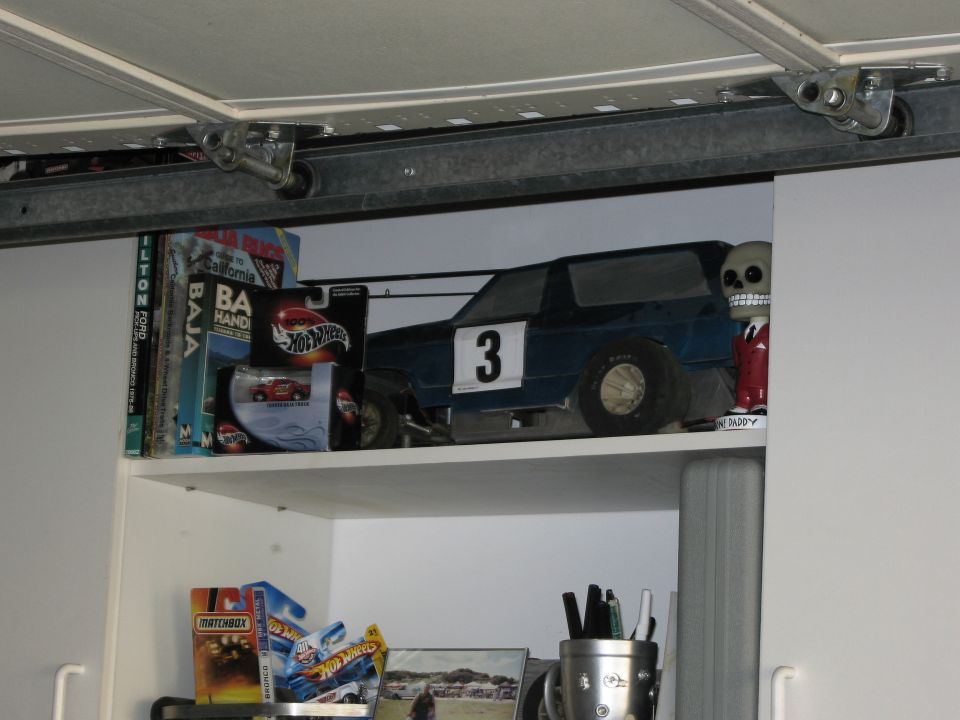 blue toy race car with number 3 on side, next to Hot Wheels packaging and a skeleton figure
