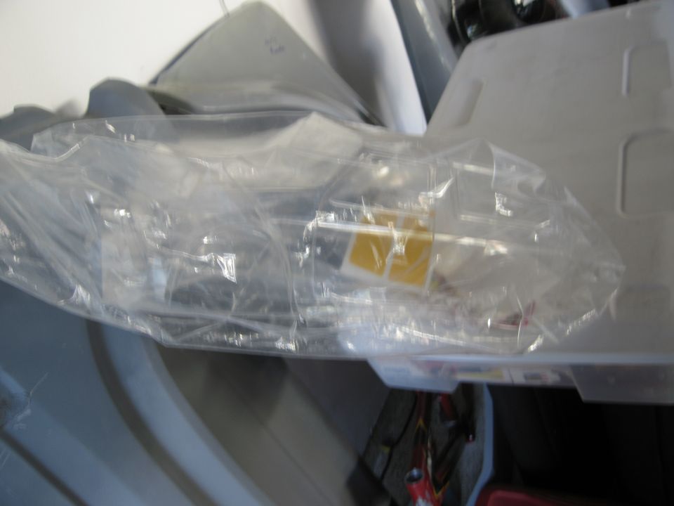 Clear plastic packaging containing model kit parts, some with yellow accents