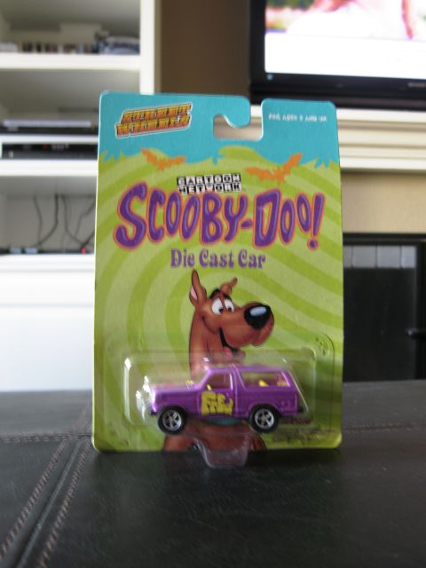 1986 Ford Bronco - A purple die-cast car, themed after Scooby-Doo, is displayed in its original packaging.
