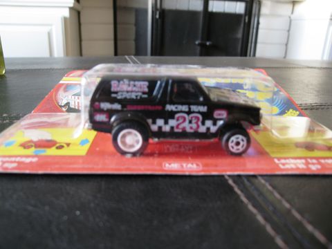 1986 Ford Bronco - A black toy SUV is displayed in its original packaging with racing graphics.