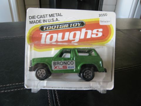 1986 Ford Bronco - A green die-cast metal Bronco XLS 4x4 toy is displayed in its original TootsieToy packaging.