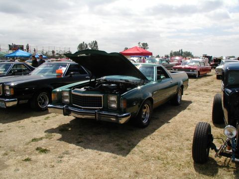 1967 Ford Ranchero - Green pickup truck displayed at a car show with its hood up, surrounded by other vehicles.