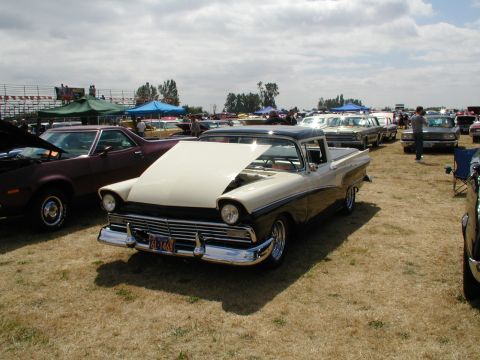 1967 Ford Ranchero - A two-tone pickup truck, likely a 1957 model, is displayed with its hood open at an outdoor car show.
