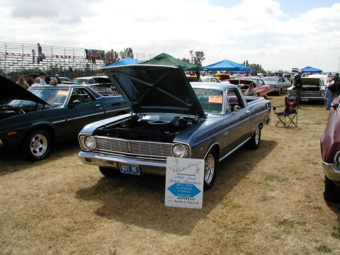 1967 Ford Ranchero - A blue 1966 Ford Falcon Ranchero is displayed with its hood up at an outdoor car show, with other vehicles and spectators in the background.