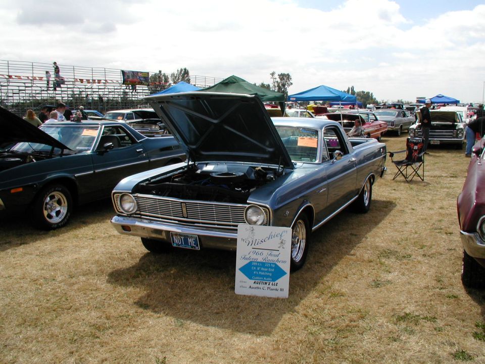 Blue 1966 Ford Falcon Ranchero with hood open at a car show. Sign says "Mischief"