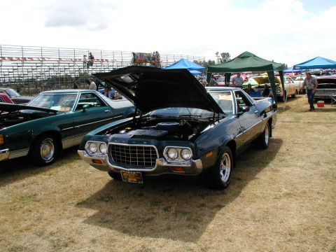 1967 Ford Ranchero - A dark green Ford Ranchero is displayed with its hood open at an outdoor car show.