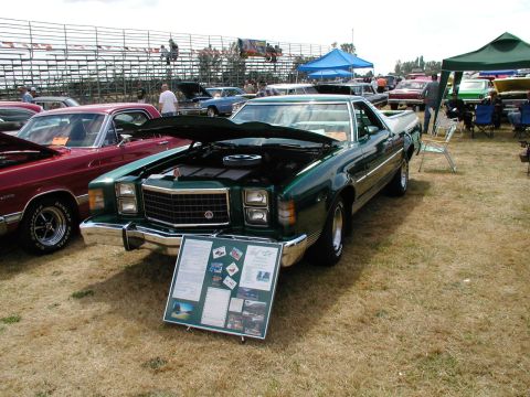 1967 Ford Ranchero - Green 1977 Ford Ranchero at a car show, hood open, with a display board in front.
