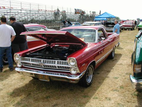 1967 Ford Ranchero - A red 1967 Ford Ranchero is displayed with its hood up at an outdoor event, surrounded by other vehicles and spectators.
