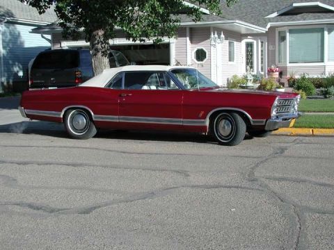 1967 Ford Galaxie - A classic red convertible with a white top is parked in front of a suburban house.