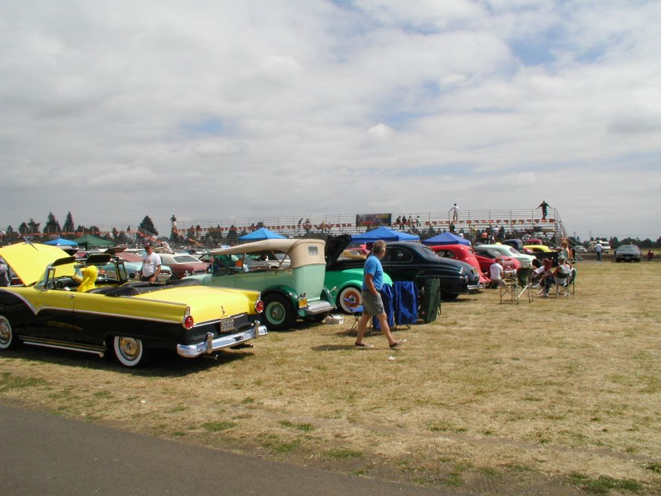 Yellow and black convertible with white wall tires and chrome trim, parked next to a green convertible