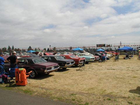 1967 Ford Ranchero - Outdoor car show with multiple classic vehicles on display under a cloudy sky.