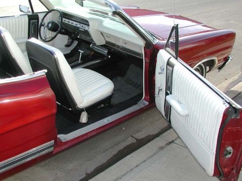 1967 Ford Galaxie - The interior of a red 1967 Ford Galaxie convertible shows white seats and door panels.