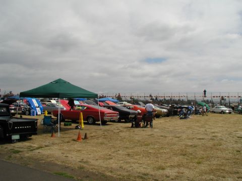 1967 Ford Ranchero - A line of classic cars, including a 1967 Ford Ranchero, are displayed at a car show under a cloudy sky.