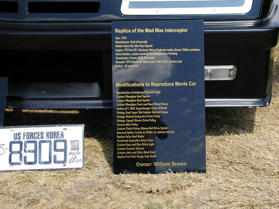 Black replica of the Mad Max Interceptor, a 1975 Ford Falcon XB, with a detailed modification plaque