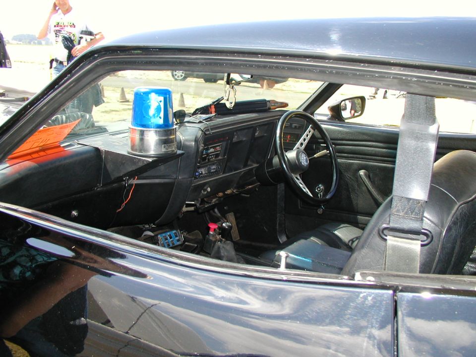 Black car interior with a blue light, steering wheel, and seats visible