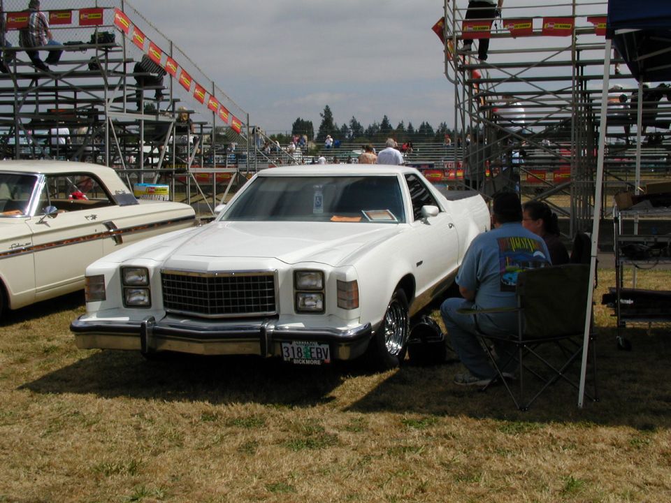 White pickup truck with a bed, chrome wheels, and a license plate reading 318 EBV