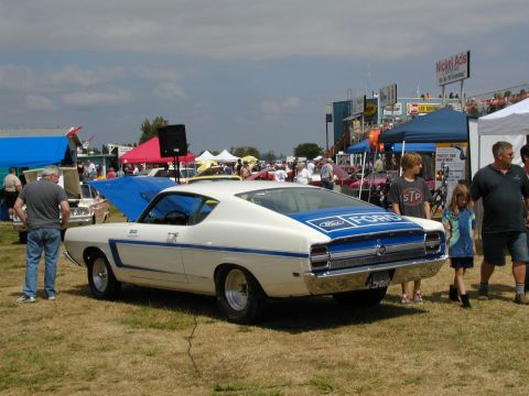 1967 Ford Ranchero - A white 1969 Ford Torino GT Fastback is displayed at an outdoor car show with spectators nearby.