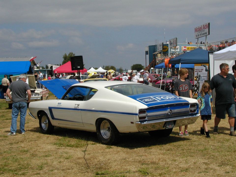 White 1969 Ford Torino GT Fastback with blue stripe and 'FORD' lettering on the rear