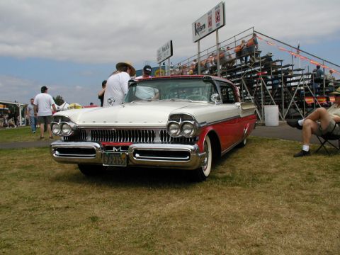 1967 Ford Ranchero - A 1958 Mercury Montclair is parked on grass with spectators in bleachers behind it.