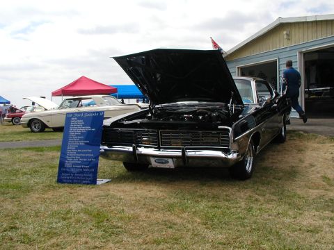 1967 Ford Ranchero - A black 1968 Ford Galaxie XL is displayed with its hood open, next to a sign detailing its features.