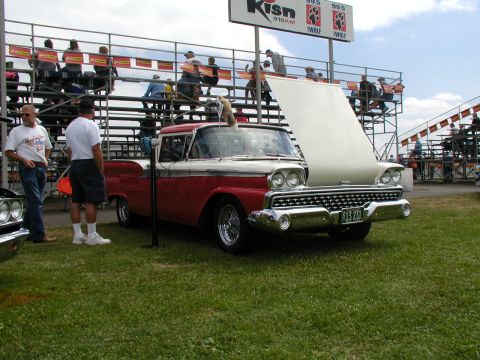 1967 Ford Ranchero - A two-tone pickup truck is parked on grass with bleachers in the background.