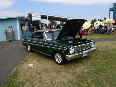 1967 Ford Ranchero - A green coupe with its hood open is parked on the grass at an outdoor event.