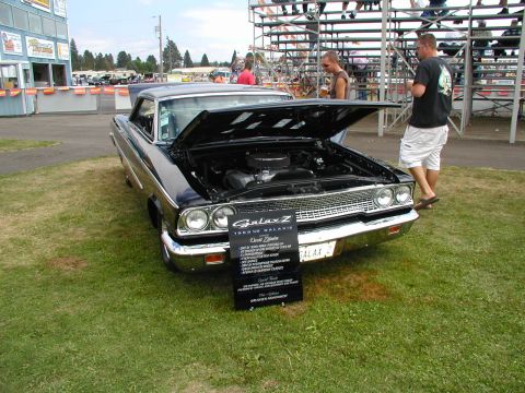 1967 Ford Ranchero - A black 1963 Ford Galaxie Z is displayed with its hood open at a car show.