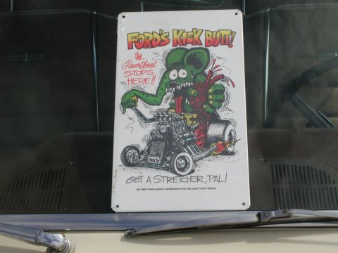 1967 Ford Ranchero - A metal sign with a cartoon rat rod is displayed on a car's dashboard.
