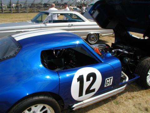 1967 Ford Ranchero - A blue race car with white stripes and the number 12 is parked next to a silver car.