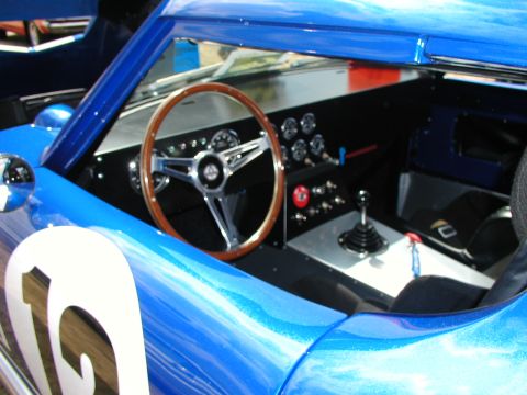 1967 Ford Ranchero - The interior of a blue race car is visible, a classic wood steering wheel and a prominent gear shifter.